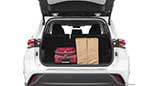 A picture taken of the rear of a Toyota Highlander's open trunk which contains a red suitcase, two brown grocery bags, and there is still plenty of extra cargo space for additional storage.