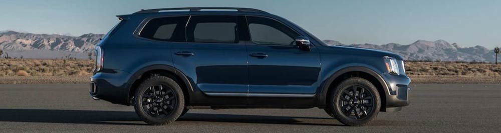 A picture of a midnight lake blue, 2023 Kia Telluride SX X-Line parked with desert and mountains in the background